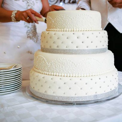 Midsection Of Couple Cutting Wedding Cake